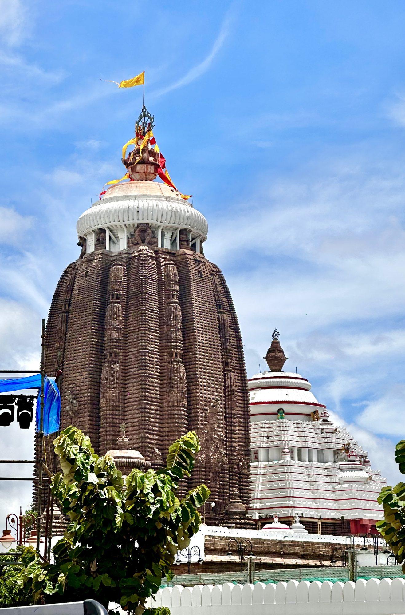 The tall deula tower of the Jagannath Temple in Puri against a bright sky with the flag above