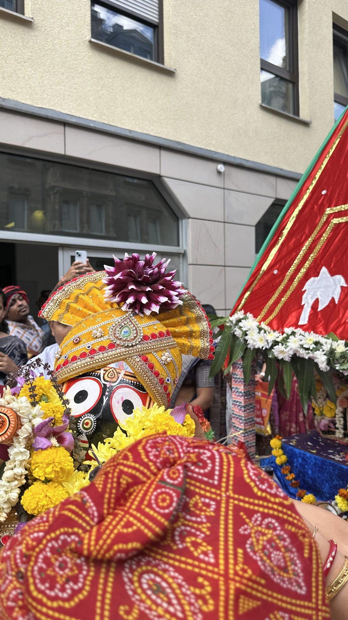 Lord Jagannath in a colourful headdress on the red chariot among yellow flowers